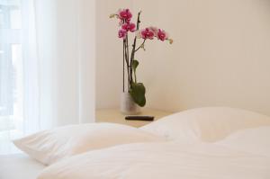 a white bed with a vase with flowers on a table at Bałtyckie-Hel in Hel