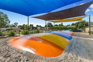 un bateau coloré dans le sable sous un parasol dans l'établissement BIG4 Tasman Holiday Parks - Bendigo, à Bendigo