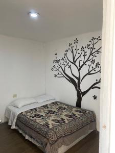 a bedroom with a tree stenciled on the wall at Casa Verde Hostal in Tlazcalancingo