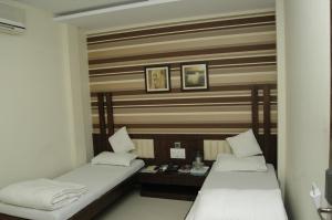 Habitación con 2 camas y mesa. en Hotel Causeway, Colaba, en Bombay