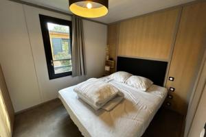 een slaapkamer met een bed met witte lakens en een raam bij Cottage - 40 m all comfort with garden in Guérande