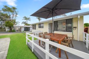 a deck with a wooden table and an umbrella at Little Palm Cabins in Lake Cathie