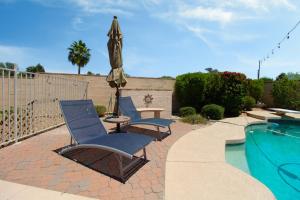 two chairs and a umbrella next to a swimming pool at Luxurious Scottsdale Guesthouse by the Pool in Phoenix