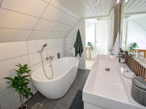 Baño blanco con bañera y lavamanos en Holiday home Tranekær IX en Tranekær
