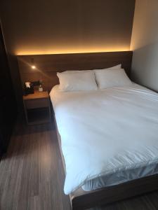 uma cama grande com lençóis brancos e uma mesa de cabeceira em Elbon The Stay em Busan