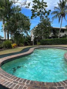 a swimming pool with a brick pathway around it at Shelby On Eshelby in Airlie Beach