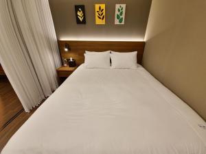 um quarto com uma grande cama branca num quarto em Elbon The Stay em Busan