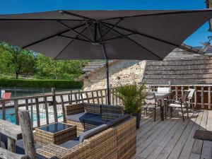 een patio met een parasol en een tafel en stoelen bij Gîte Terrasson-Lavilledieu, 3 pièces, 4 personnes - FR-1-616-263 in Terrasson