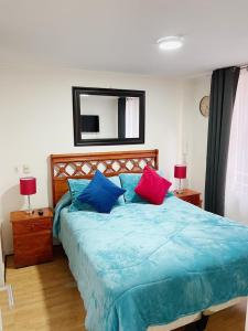 a bedroom with a bed with blue and red pillows at Departamento de 1 Dormitorio in Santiago