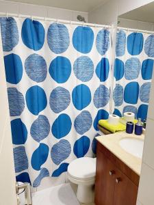 a bathroom with a toilet and a blue and white shower curtain at Departamento de 1 Dormitorio in Santiago