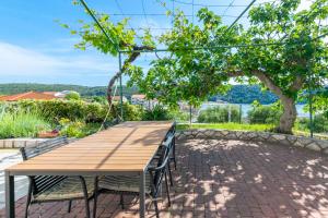 a wooden table and chairs on a patio with a tree at Apartments Zeljko in Kampor