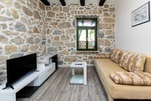a living room with a couch and a tv and a stone wall at Apartments Zeljko in Kampor