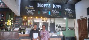 two men standing in front of a bar at Mushtinal Guest House in Ende
