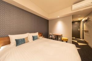 a bedroom with a large white bed with blue pillows at Tokyu Stay Sapporo Odori in Sapporo