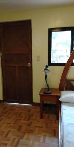 a bedroom with a door and a table with a lamp at Hondelz Budget Homestay in Busuanga