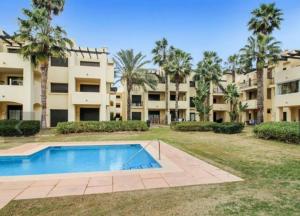un complejo de apartamentos con piscina y palmeras en Penthouse Apartment - Roda Golf & Beach Club, en San Javier