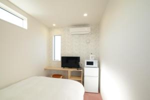 Hotel Cradle Cabin Tateyama في تاتياما: غرفة نوم بسرير ابيض وتلفزيون