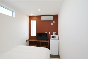 um pequeno quarto com uma cama e uma televisão em Hotel Cradle Cabin Tateyama em Tateyama