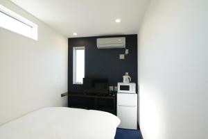 een slaapkamer met een wit bed en een magnetron bij Hotel Cradle Cabin Tateyama in Tateyama