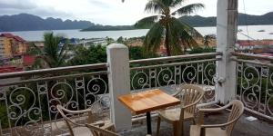 a table and chairs on a balcony with a view of the water at Hub Backpackers Hangout in Coron