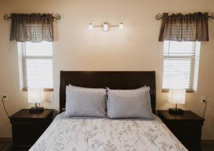 a bedroom with a bed with two night stands and two windows at Log Cottages at Bryce Canyon #1 in Cannonville