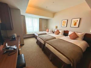 a hotel room with three beds and a television at Tokyo Bay Maihama Hotel in Urayasu