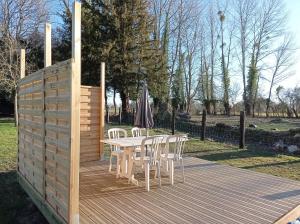 een houten terras met een tafel en stoelen en een parasol bij Paisible Cahute in La Poterie-Mathieu