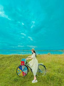 a woman is sitting on a bike in a field at Suối Đá F-Glamping 2026 in Thiện Giáo