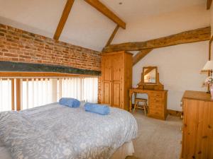 a bedroom with a bed and a table and a mirror at Hadleigh Farm Barn in Gayton