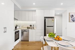 a white kitchen with a table and a refrigerator at Ambrosia - East End Hillside Haven in Adelaide