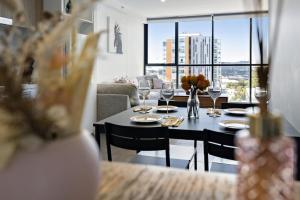 een eetkamer met een tafel en uitzicht op een woonkamer bij Isaac - The Cityscape View Apartment in Adelaide