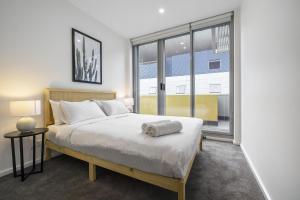a bedroom with a bed and a large window at Meadow - The York Skyline Apartment in Adelaide