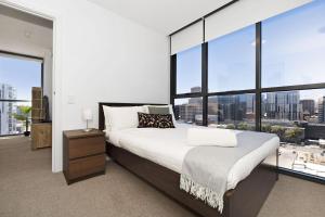 een slaapkamer met een groot bed en grote ramen bij Isaac - The Cityscape View Apartment in Adelaide