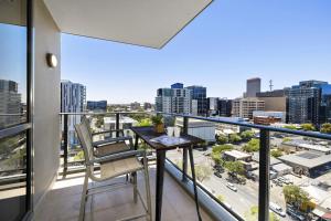 een balkon met een tafel en stoelen en een stad bij Isaac - The Cityscape View Apartment in Adelaide