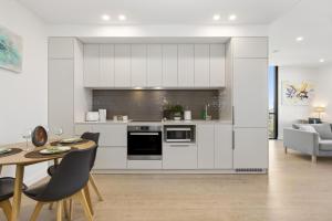 a kitchen with white cabinets and a table and chairs at Oleria - Serene Bohem Retreat in Adelaide