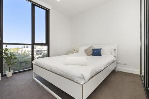 a white bedroom with a large bed and a window at Oleria - Serene Bohem Retreat in Adelaide
