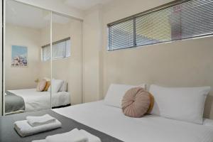 Habitación blanca con 2 camas y espejo. en Azalea - Rundle Mall Edge Residence on York, en Adelaida