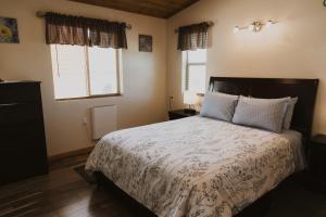 a bedroom with a large bed and two windows at Log Cottages at Bryce Canyon #2 in Cannonville