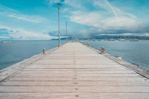 a wooden pier in the water with boats at Hotel Bambou in Les Trois-Îlets