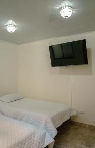 um quarto com uma cama e uma televisão de ecrã plano na parede em Los Ríos em Pereira