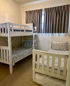 Ce lit se trouve dans un dortoir doté de 2 lits superposés blancs et d'une fenêtre. dans l'établissement Top-floor beachside apartment with views, à Casuarina