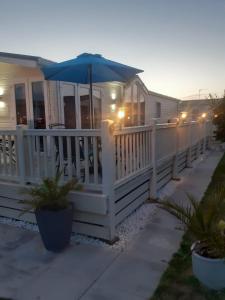 a house with a white fence and an umbrella at Luxury Caravan - WI-FI and SMART TV newly installed in Rhyl