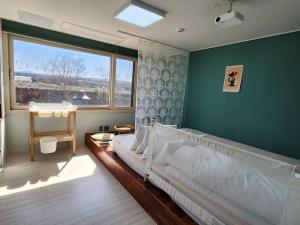 ein Schlafzimmer mit einem großen Bett und einem großen Fenster in der Unterkunft Again Here Jeju in Jeju-do