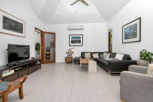 a living room with a couch and a tv at Belle Escapes Luxury Reef Villa Palm Cove in Palm Cove