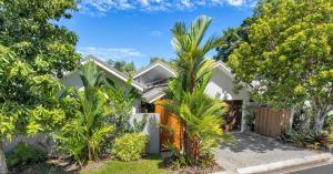 a house with palm trees in front of it at Belle Escapes Luxury Reef Villa Palm Cove in Palm Cove