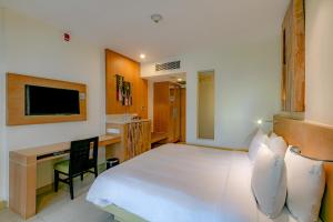 a bedroom with a bed and a desk and a television at Holiday Inn Resort Baruna Bali by IHG in Kuta