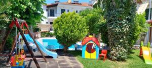 a yard with a playground with a slide and trees at VitaminSea Apartments in Kallithea Halkidikis