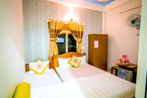 a bedroom with two beds with yellow pillows at Phuc Hau Hotel - Ly Son in Ly Son