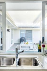 a kitchen sink with a view of a living room at Bokarina Seaside Escape - Only steps to the Beach in Kawana Waters
