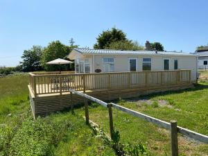a mobile home with a deck and an umbrella at Mountain View Lodge 2 in Holyhead